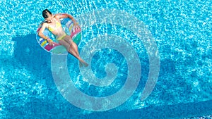 Acrive girl in swimming pool aerial top view from above, kid swims on inflatable ring donut , child has fun in blue water