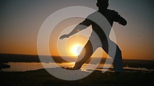 Acrobat makes torsion on the hands, sunset, slow-motion