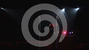 Acrobat performs exercises on the bar in the circus arena