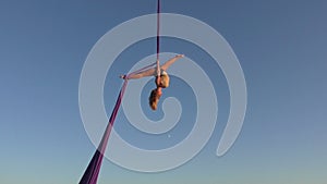 Acrobat woman hanging on silk in the sky.