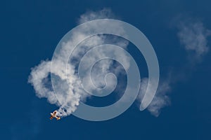 Acrobatic airplane spiraling towards the ground leaving smoke trail behind