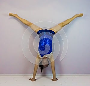 Acrobatic gymnastics a middle split handstand preformed by a young transgender girl wearing a blue shiny leotard