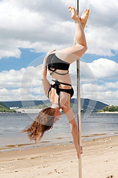 Acrobatic performance brunette in swimsuit on pole for dancing