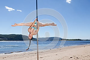 Acrobatic performance laughing brunette woman in swimsuit on pole for dancing