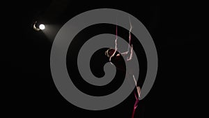 Acrobatic performance of a young woman circus performer on airy silk. Equilibrium circus gymnast spinning in the air on