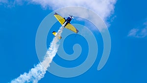 An acrobatic plane, flying in the blue sky with white clouds, doing acrobatics