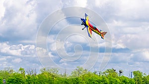 An acrobatic plane, flying in the blue sky with white clouds, doing acrobatics