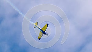 An acrobatic plane, flying in the blue sky with white clouds, doing acrobatics