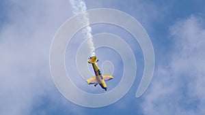 An acrobatic plane, flying in the blue sky with white clouds, doing acrobatics