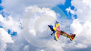 An acrobatic plane, flying in the blue sky with white clouds, doing acrobatics