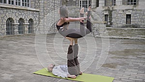 Acrobatic yoga for couples. Pose of asana `Airplane`. Yoga pose for two men and women. Outdoors