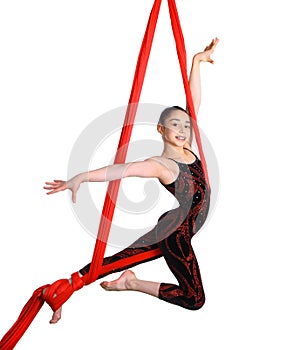 Acrobatic young girl exercising on red fabric rope