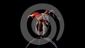 Acrobats spin and perform various stunts on the stage. Black background