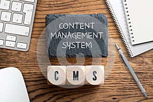 Acronym CMS on wooden cubes and writing slate with explanation `Content Management System`
