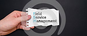 Acronym FSM or Field Service Management. Person holding a piece of paper with text