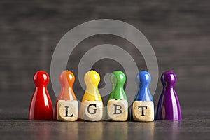 Acronym LGBT written on wooden cubes with pawns in the colors of the rainbow flag