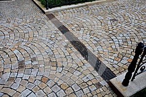 Across the path there is a channel with a metal grid for drainage interlocking paving. the water is drained from the surface into