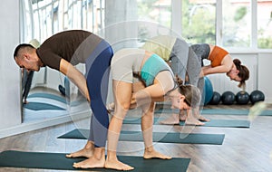 Acroyoga, two sporty people practice yoga in pair, couple doing stretching exercise standing pose half forward bend at