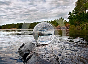 Acrylic crystal ball on rock by a lake