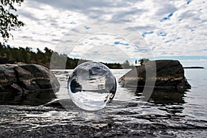 Acrylic crystal ball on rock by a lake