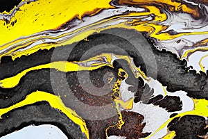 Acrylic Fluid Art. Yellow black waves and gold inclusions. Abstract stone background or texture
