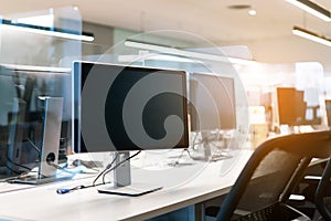 Acrylic plexiglass separator setting on the desk with monitor in the office. New normal Concept for social distancing in offices