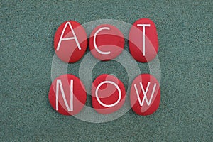 Act Now slogan, Climate Emergency protest sign composed with red colored stones over green sand photo