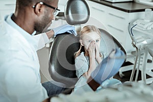 Small blue-eyed girl being afraid of dentist equipment