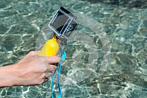 Action camera with a yellow float in the girl`s hand. against the backdrop of crystal clear water in the pool