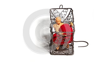 Action figure sitting in cage and holding red heart on white background. Concept of Love and imprisonment