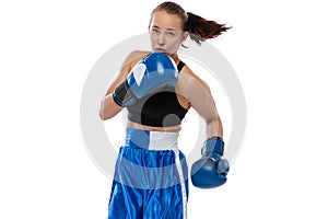 In action, motion. Young girl, professional boxer practicing in boxing gloves isolated on white studio background