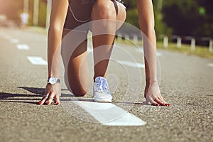 Action packed close-up image of a female athlete At low start for a sprint run on a track