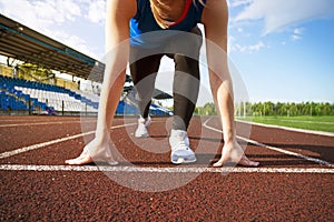Action packed image of a female athlete leaving the starting blocks for a sprint run on a track