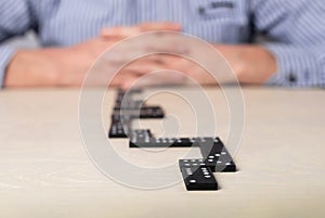 Action plan, strategy, risk assessment concept. Man with crossed hands thinking about next step while playing domino.