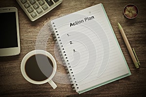 Action Plan text on book note with cup of coffee,