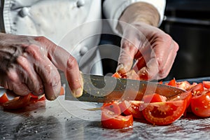 action shot of chef dicing tomatoes with a sharp knife
