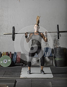 Action shot of female powerlifter practicing clean and jerk in gym photo