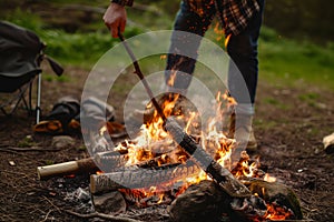 action shot of friend stoking campfire with stick