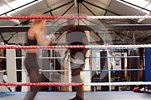 Action Shot Of Male Personal Trainer Sparring With Female Boxer In Gym Using Training Gloves