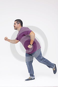 Action shot of a middle aged man chasing someone, in hot pursuit running at a fast pace. Wearing a purple waffle shirt and jeans.