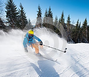 Action shot of professional skier taking selfies photo with a camera on selfie stick while skiing