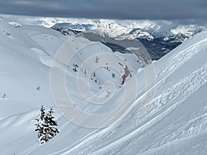 Action shot of a young female snowboarder riding down a steep ungroomed slope. photo