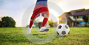 Action sport outdoors of kids having fun playing soccer football for exercise in community rural area under the twiligh