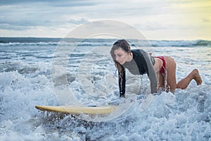 Action of young woman try to step standing on the surfboard in the med of the ocean, riding on the wave attemption skill training