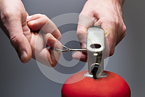 Actions in case of fire. Pull the safety pin out of the fire extinguisher by the ring. Men`s hands close-up. Safety measures in