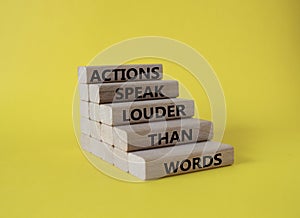 Actions speak louder than Words symbol. Wooden blocks with words Actions speak louder than Words. Beautiful yellow background.
