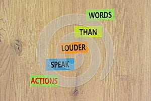 Actions speak louder words symbol. Concept words Actions speak louder than words on colored paper. Beautiful wooden background.