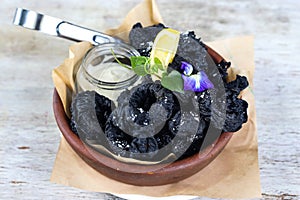 Activated Charcaol Battered Calamari Fritti with dip and lime served in a dish isolated on grey background side view of snacks