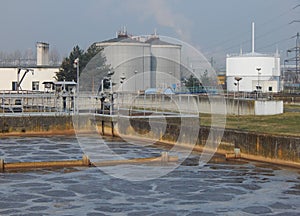 Activated sludge tank with aerated wastewater and anaerobic digesters in the background
