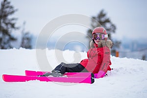 Active adorable preschooler caucasian girl portrait with ski in helmet, goggles and bright suit enjoy winter extreme sport